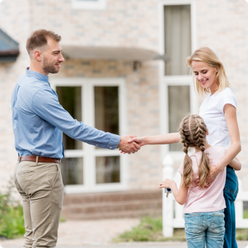Lady standing with a little girl shaking hand with a men in blue