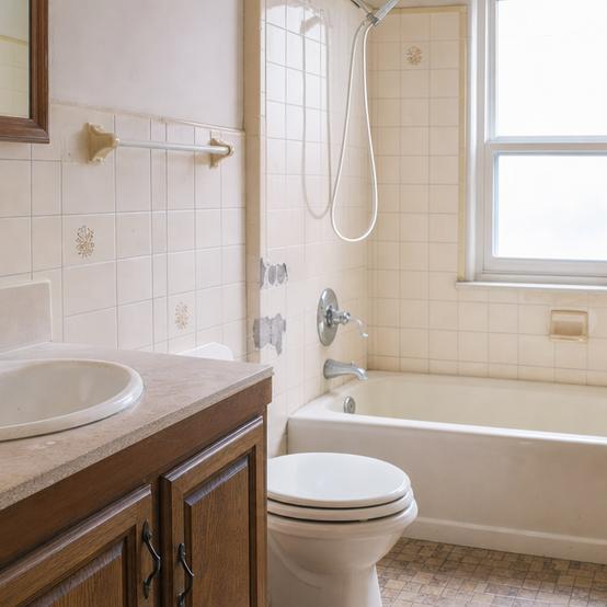 Dated bathroom with worn tile and an older vanity