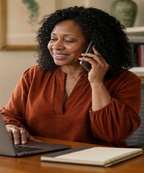 Homeowner smiling on the phone at her laptop while contacting SellMyHouse.co